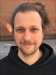 Portraitbild unseres Mitarbeiters Leo vor einer Steinwand im Freien.