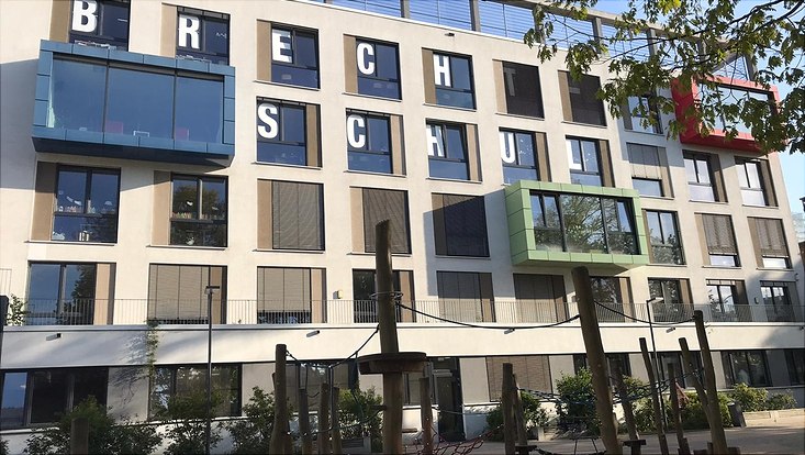 Das Schulgebäude der Brecht Schule Hamburg mit einem Klettergerüst auf dem Schulhof