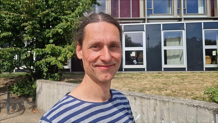 Andreas Bonnet steht vor dem Fakultätsgebäude und schaut in die Kamera
