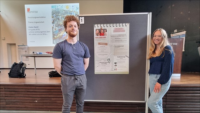 Zwei Studierende vor einem Poster