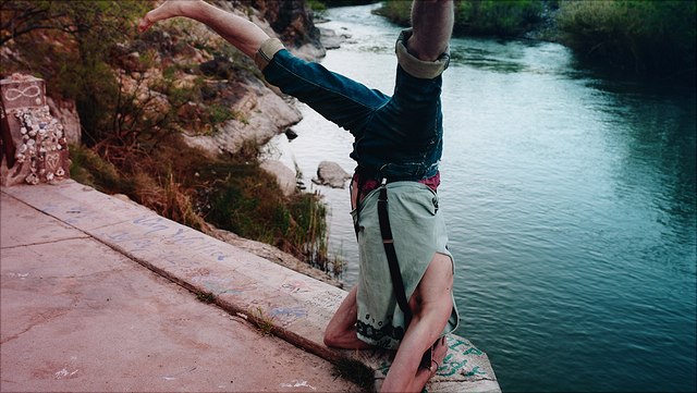 Kopfstand an Klippe über einem Fluss