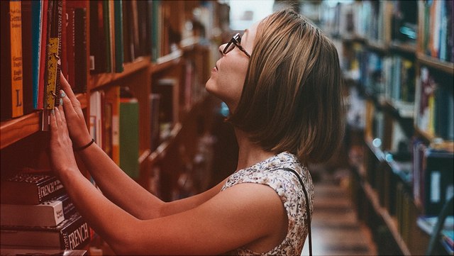 Frau in Bibliothek vor Bücherregal