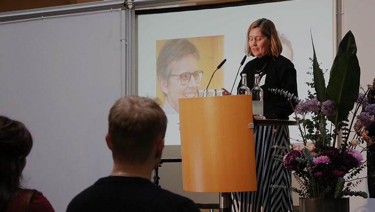 5-733x414 Blick aus Publikum. Frau auf Bühne. Präsentation im Hintergrund.