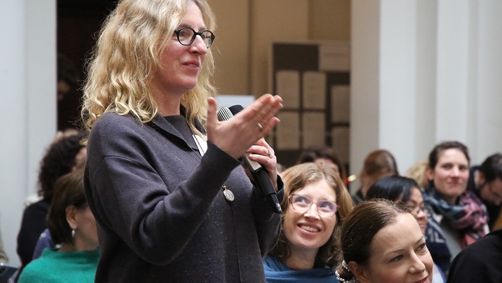 8-733x414 Frau stehend im Publikum mit Mikrofon. Publikum blickt auf die Frau.