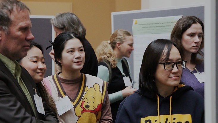 9-10-733x414 4 Personen blicken gemeinsam auf ein Poster. Perspektive von vorne.