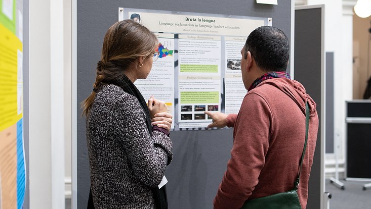 22-733x414 Frau und Mann blicken auf ein Poster. Blick von hinten.