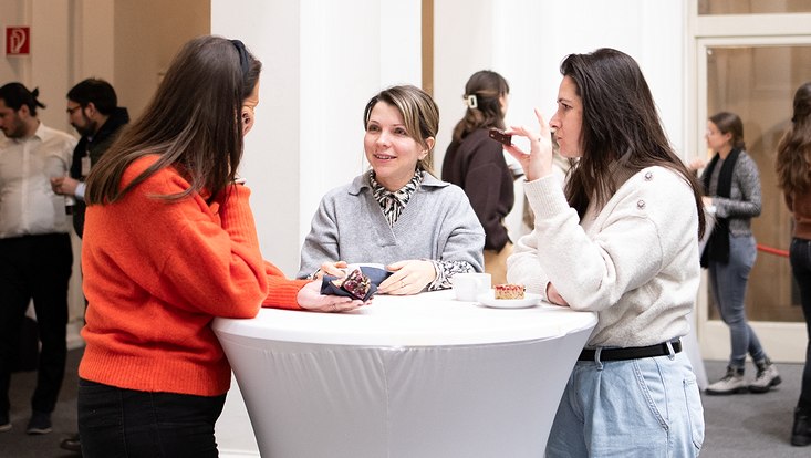 26-733x414 Drei Frauen im Gespräch um einen Stehtisch.