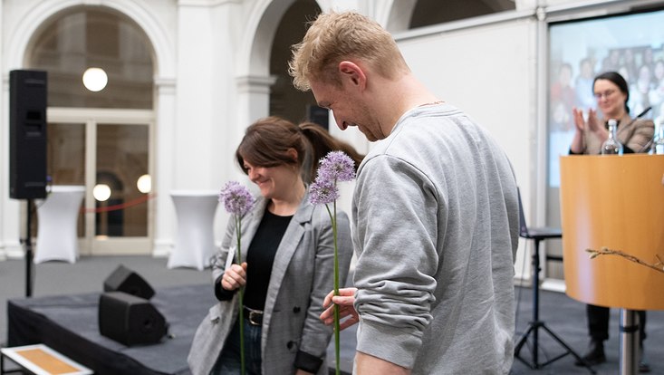 30-733x414 Zwei Personen von der Seite mit Blume in der Hand.