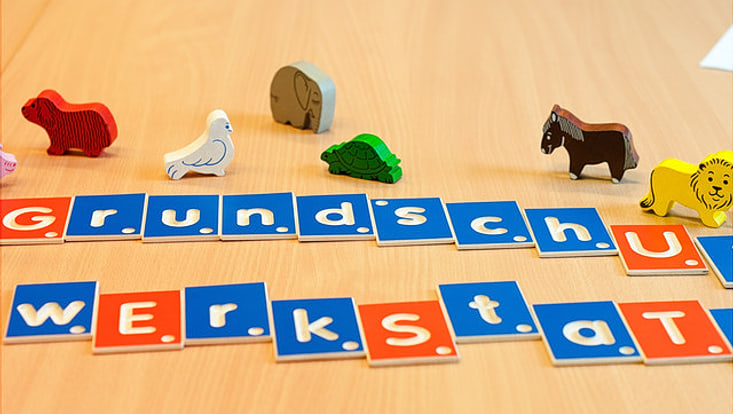 Spielzeugbuchstaben mit der Aufschrift Grunschuld Werkstatt auf einem Tisch