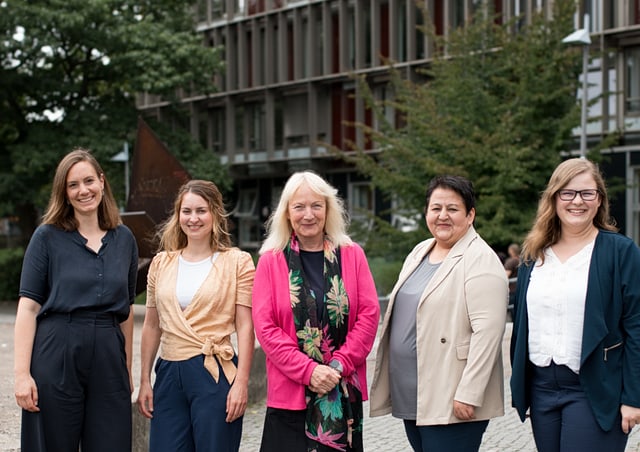 Hilla Franken, Lena Borlinghaus-ter Veer, Telse Iwers, DIlbar Ernazarova und ALina Kunze stehen nebeneinander vor dem Gebäuder der Fakultät und lächeln in die Kamera