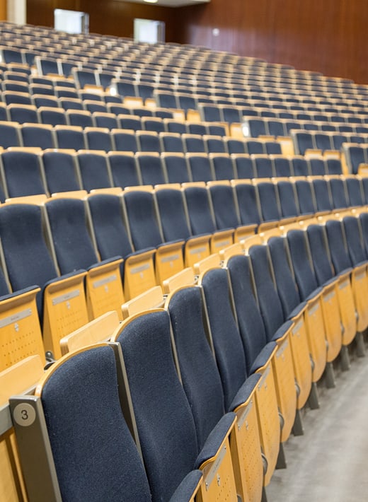 Seitlicher Blick auf mehrere Reihen hochgeklappte Stühle im Hörsaal