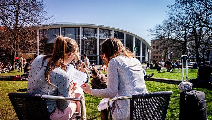 Studierende auf der Wiese vor dem Audimax