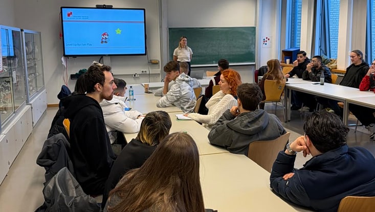 Bild eines Seminarraums, in dem Julia Levin vorne steht und Studierende im Seminarraum schauen auf sie und hören zu