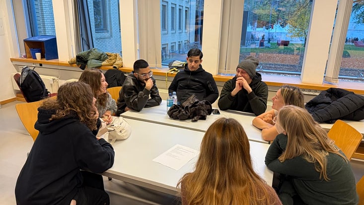 levin-hass-im-gaming-2025-4-733x414 Acht Studierende sitzen einander zugewandt an einem Gruppentisch und unterhalten sich