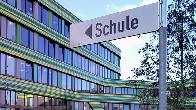 Wegweiser Schule mit Schulgebäude im Hintergrund