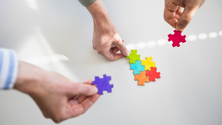 Hände die ein Puzzle zusammenstellen