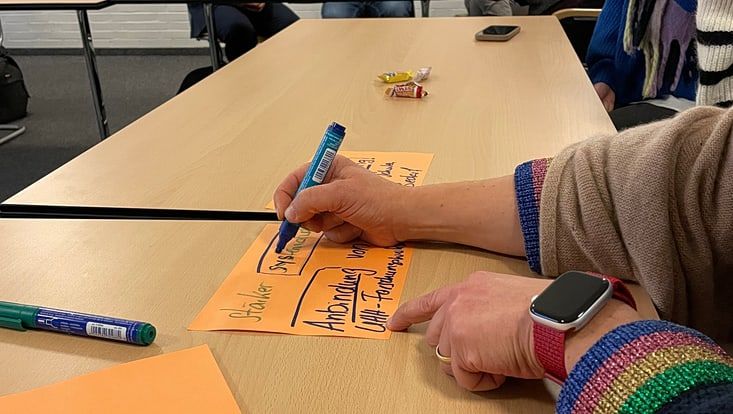 Momentbildaufnahmen der Tagung (Hand die eine Karte für ein Flip-Chart beschriftet)
