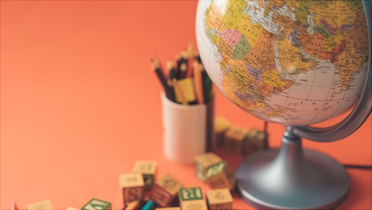 Globus, Stifte und Buchstabenwürfel stehen auf einem Tisch