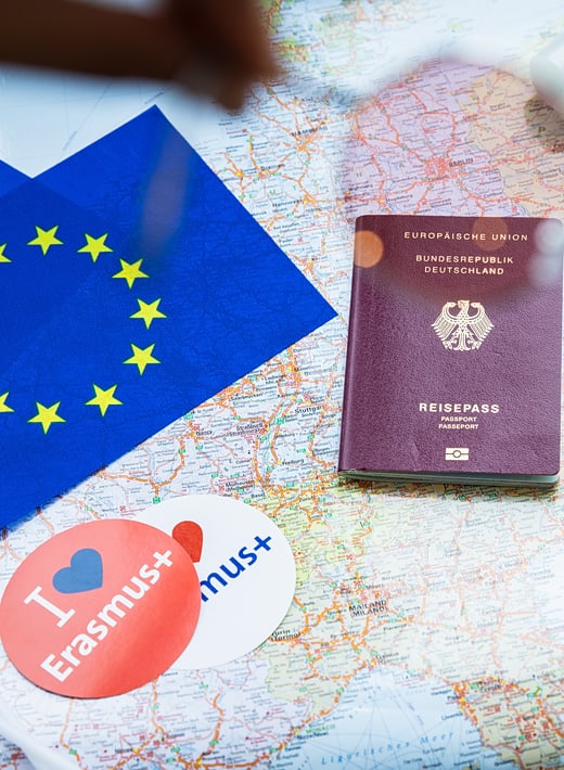 Schreibtisch, auf dem eine Landkarte, ein Reisepass und ein Erasmus-Sticker liegen