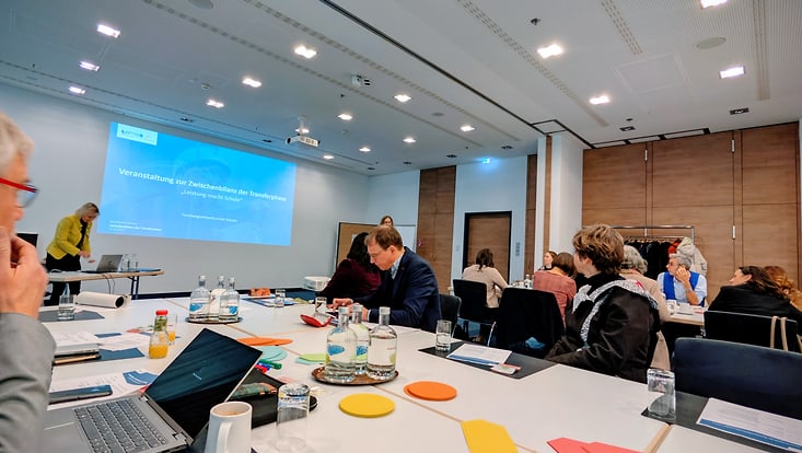 whatsup-2025-12-julia-bilanztagung-berlin-jpg-png-733x414 Tagungsraum mit Tischen und Präsentation