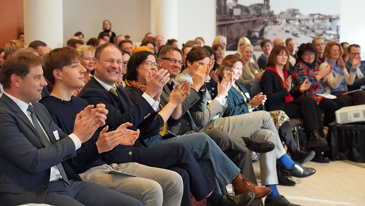 whatsup-2025-11-julia-dresden-jpg-png-733x414 Sitzende und applaudierende Zuschauer:innen im Tagungsraum