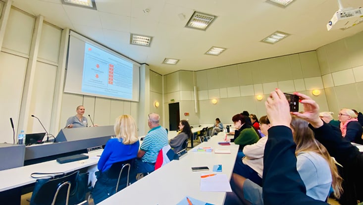 Britta Lübke auf MNU-Kongress Frau an Podium während Vortrag