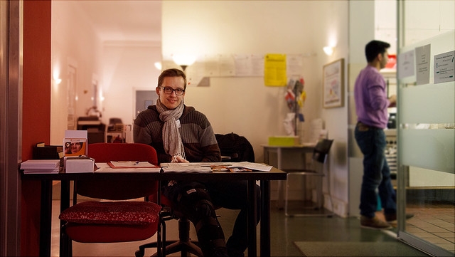 Mann sitzt an Tisch mit Infobroschüren.