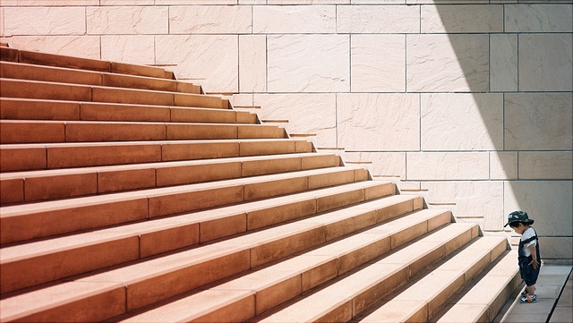 Kleinkind steht vor langer Treppe.