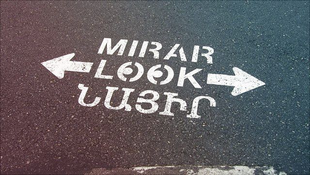 Die Aufforderung nach rechts und links zu schauen steht in drei Sprachen auf dem Asphalt.