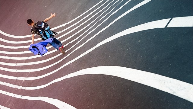 Junge läuft auf welligen Linien auf der Straße.