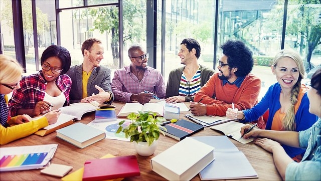 Junge Erwachsene sitzen am Tisch und arbeiten in Kleingruppen.