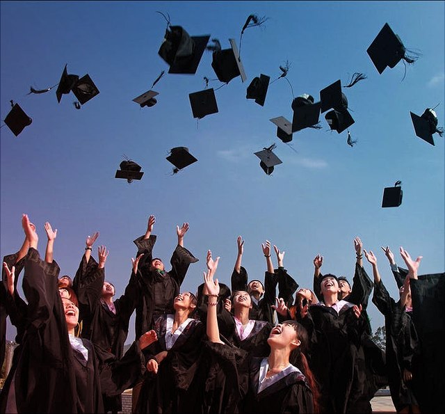 AbsolventInnen werfen ihre Diplomhüte in die Luft