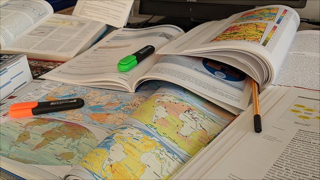 Bücher, Landkarten und Stifte auf einem Schreibtisch