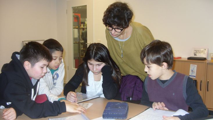 4 Kinder und eine Lehrerin betrachten Texte