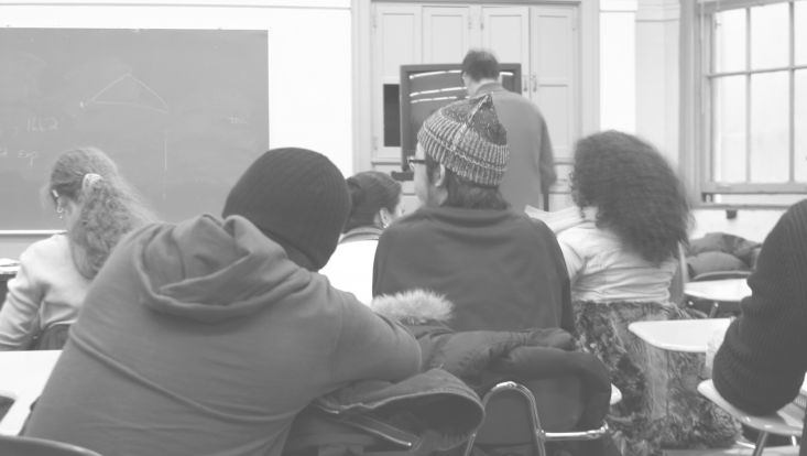 Jugendliche sitzen im Klassenzimmer, Bild von hinten aufgenommen.