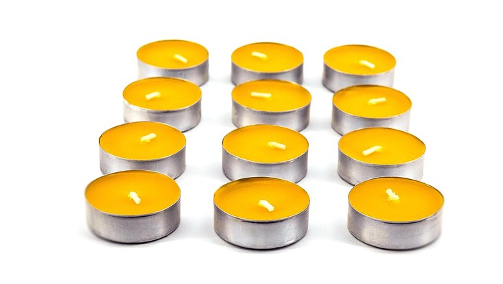 Darstellung der Zahl 12 durch 12 gelbe Teelichter, die in drei Reihen aufgestellt sind.