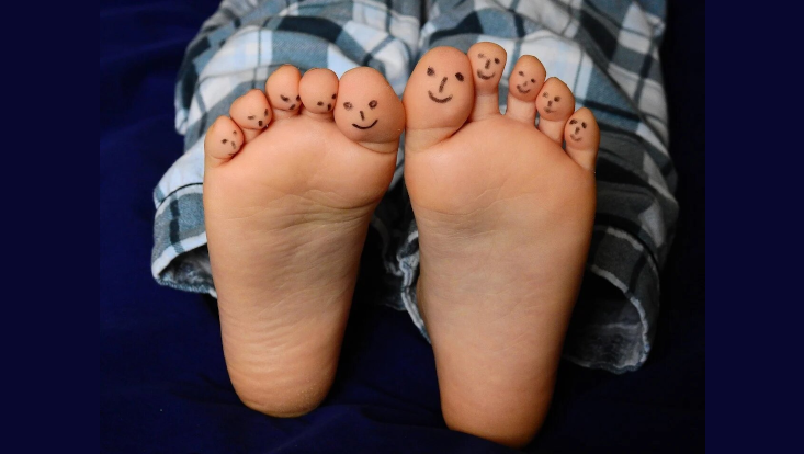 Darstellung der Zahl 10 durch zehn Zehen mit aufgemalten Smileys.