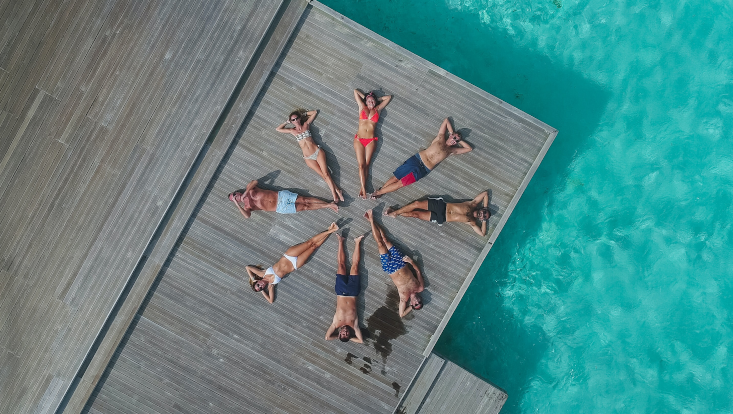 Darstellung der Ziffer 8 durch acht Menschen, die in Kreisform auf einem Steg liegen.