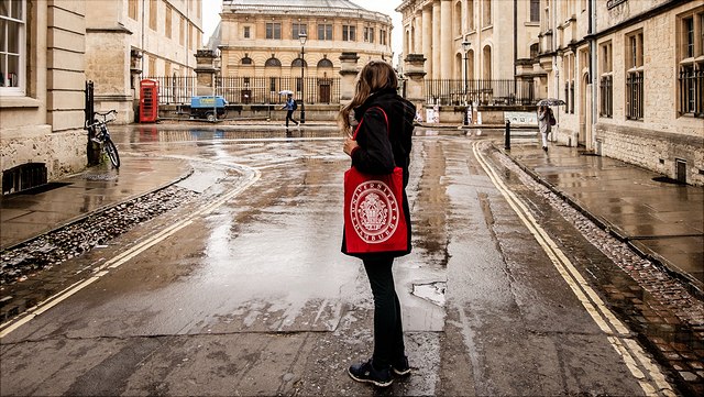 Studierende mit rotem Stoffbeutel mit dem Logo der Universität Hamburg steht auf der Straße und schaut nach hinten