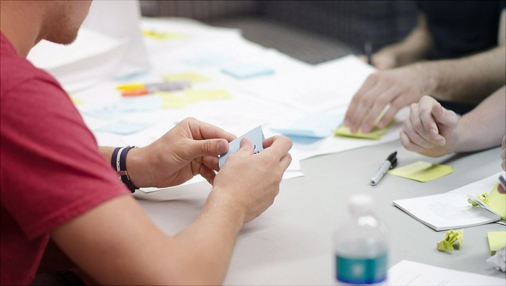 Three people sitting at a table working with sticky notes