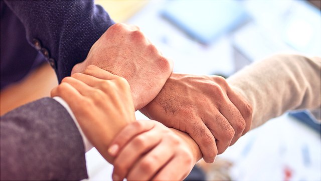 4 Haende umfassen das Handgelenk des Nachbarn, bildet ein Quadrat