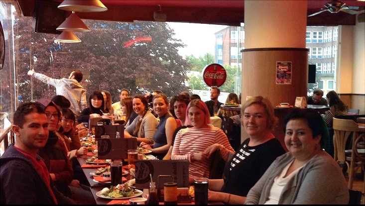 Eine Gruppe von Studierenden sitzen am Tisch und essen Burger.