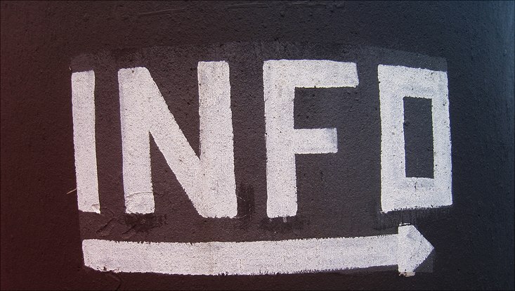 Das Wort "Info" mit Pfeil nach rechts drunter mit Kreide auf Tafeluntergrund