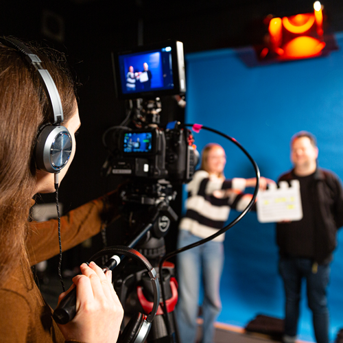 medienzentrum Zwei Mitarbeiter arbeiten am PC vor Filmplakaten