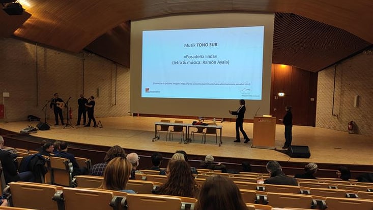 Tono Sur auf der Bühne links, rechts Power-Point-Präsention der Eröffnungsfeier
