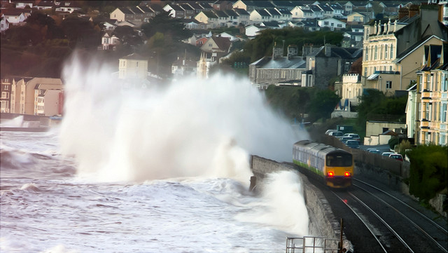 Wellen treffen auf Land und ein zug fährt daran vorbei