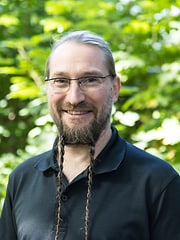 Person im Profil vor grünem Busch