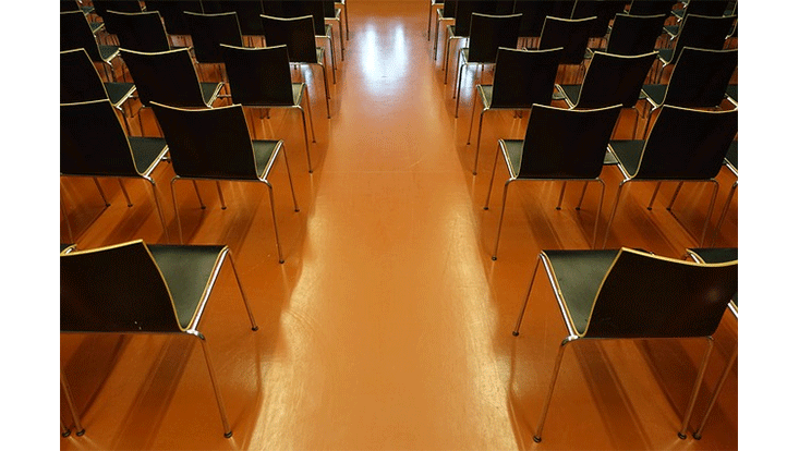 Stuhlreihen in einem Saal, rechts und links vom Mittelgang