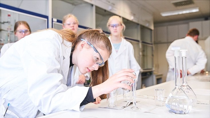 Eine Schülerin beim Abmessen der Lösungen für den Versuch „Der chemische Sonnenuntergang“.