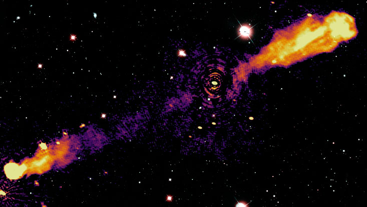 Die Abbildung zeigt kombinierte Aufnahmen von Daten, die mit Radioteleskopen und optischen Teleskopen aufgenommen wurden. Die feuerartigen Streifen in der Illustration sind sogenannte Jets, die weißen Punkte sind Sterne und Galaxien, die von Freiwill